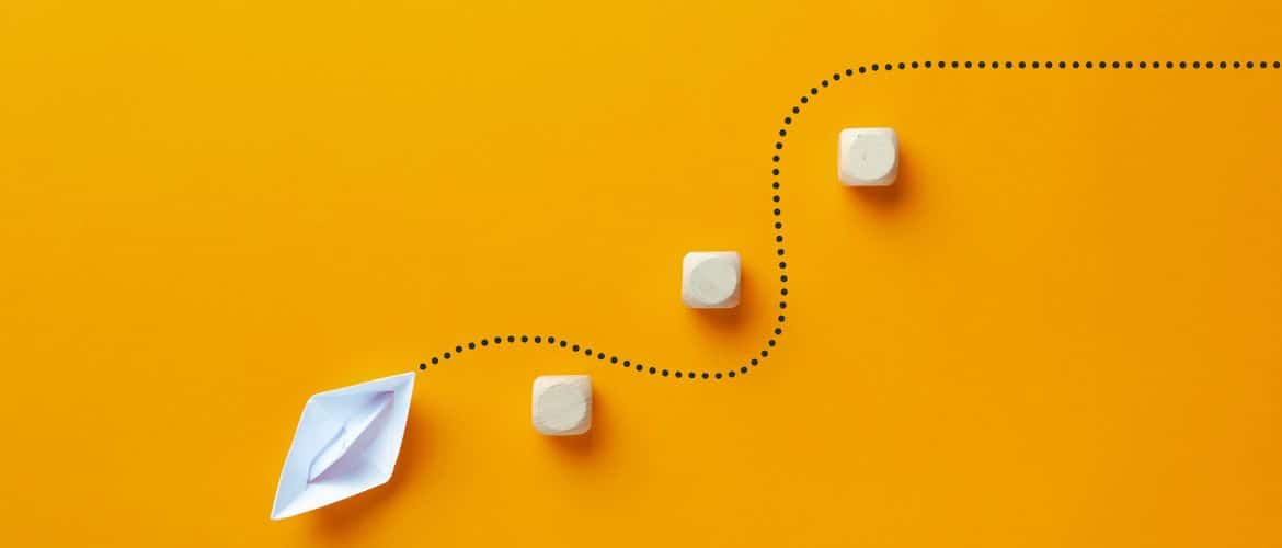 A paper boat following a dotted path around obstacles, symbolizing the journey and challenges in IT outsourcing, as discussed by Allied Global.