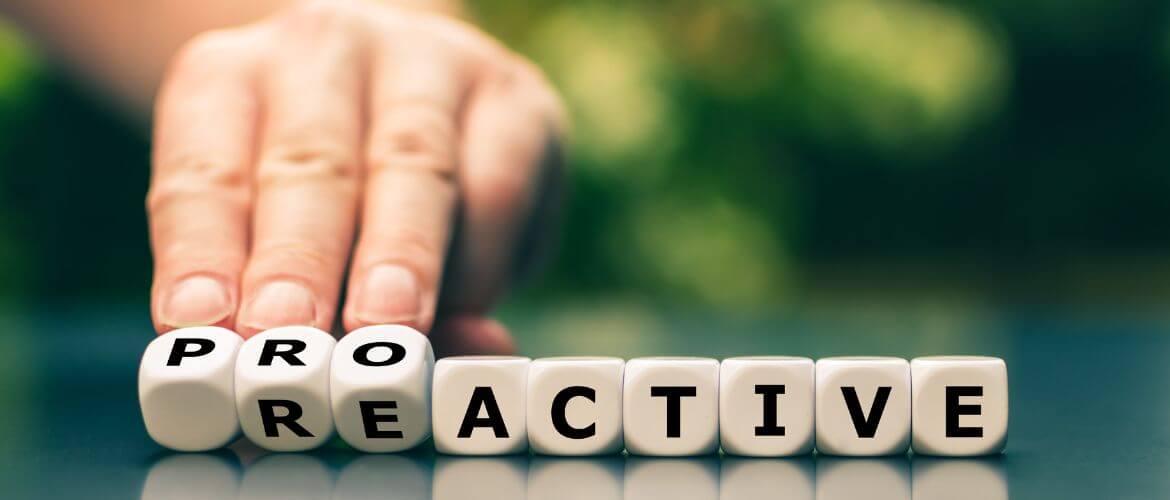 Hand adjusting blocks spelling 'Proactive' and 'Reactive,' symbolizing the shift towards proactive strategies.